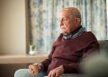 An elderly, lonely man sits in an armchair.