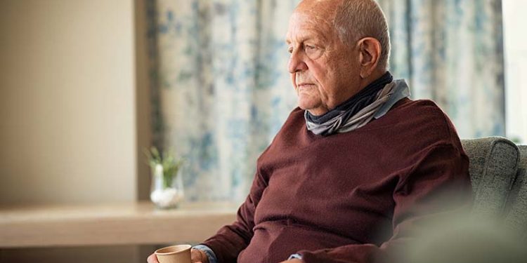 An elderly, lonely man sits in an armchair.